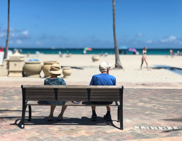 Elder couple sitting on a bench at the beach